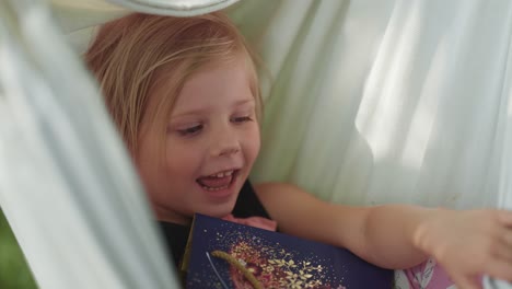 A-happy-little-girl-swings-in-the-hammock-holding-a-gift-bag