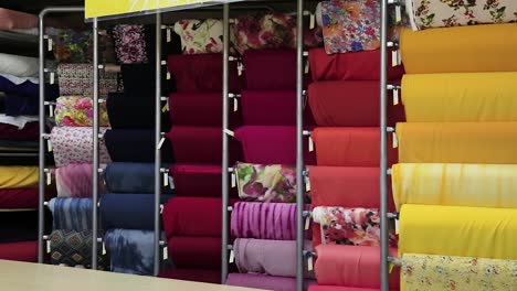 Camera-pan-of-colorful-big-rolls-of-cloth-samples-vertically-organized---interior-shot-sharp-focus