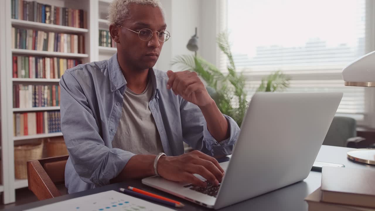 Thoughtful african man at home office desk with laptop thinking of inspiration