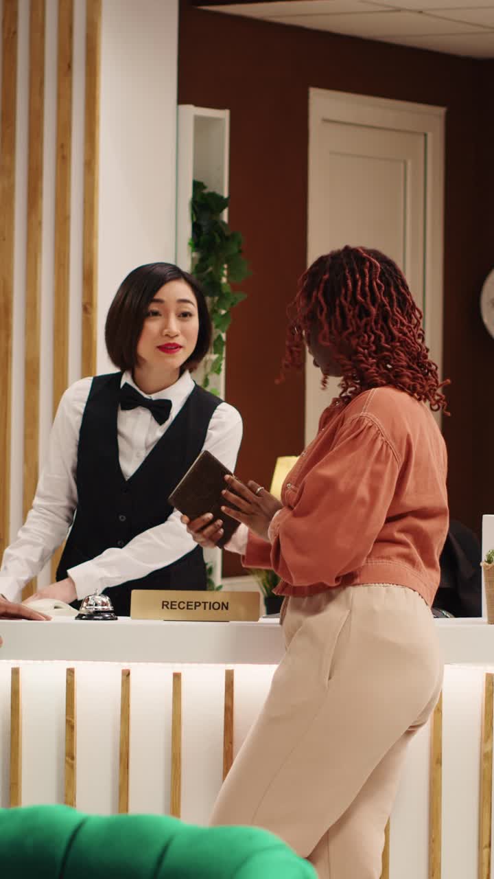 Reception di un hotel con receptionist e clienti
