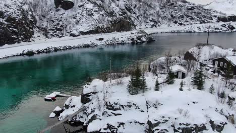 drone view in tromso area in winter flying circling over a small island with snow connected with a hanging wooden bridge in norway