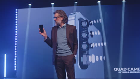 hombre presentando un teléfono inteligente en una conferencia de tecnología