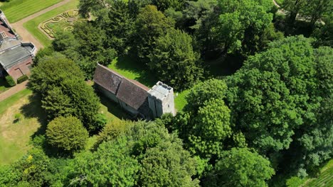 A-high-angle-roll-shot-of-Lady-Magdalene-church,-following-the-circle-of-trees-around-the-church