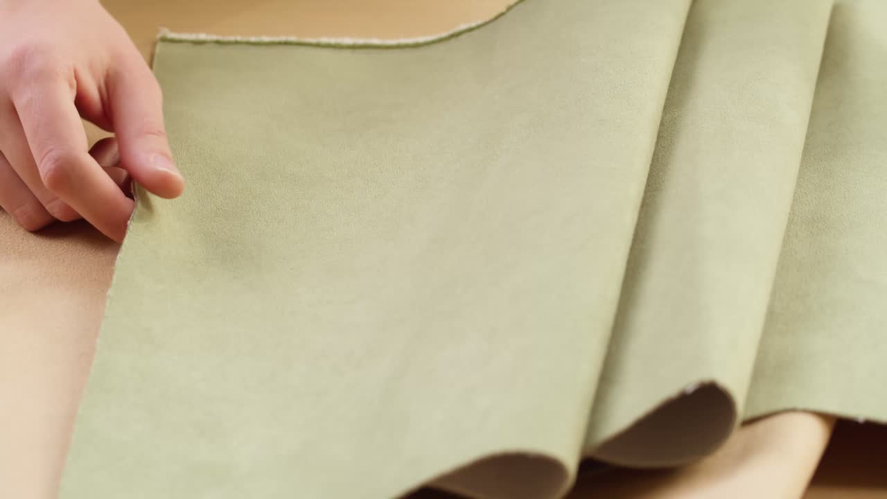 Detail rukou rozkládajících a uhlazujících jemnou zelenou látku