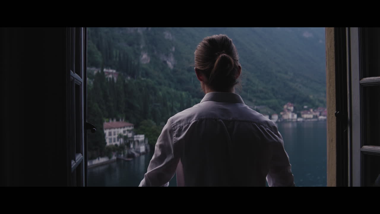 Person looking at a scenic lake view from a window