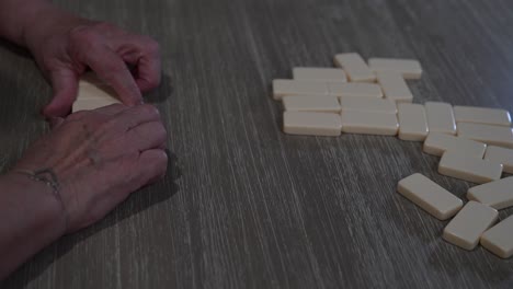 senior woman draws from a pile of dominoes