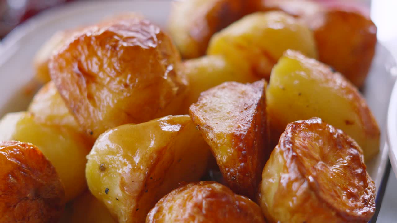 Croccanti e squisite patate arrosto britanniche dorate in una ciotola da portata con luce naturale. Delizioso contorno per una cena arrosto. Filmato 4K di alta qualità.