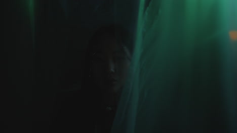 portrait of beautiful asian girl smiling at camera among cellophane curtains