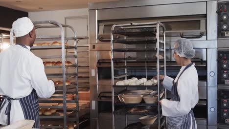 happy diverse bakers in bakery kitchen preparing rolls in slow motion