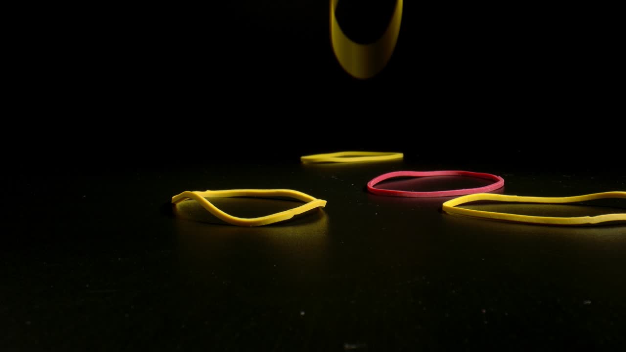 Colorful ring shaped rubber bands close-up. Coloured gum band falling on black table.