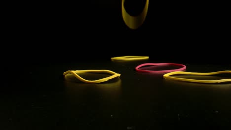 colorful ring shaped rubber bands close-up. coloured gum band falling on black table.