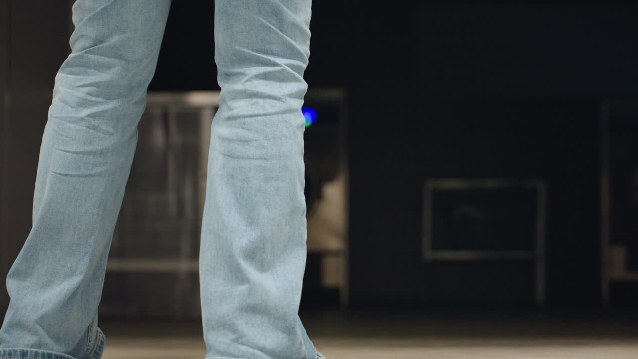 Back view of owner operator bends to roll up steel shutter of laundry room, hair moving, light jacket, motion blur, indoor corridor setting, clean space, morning routine, equipment inside dim