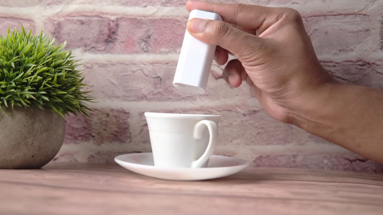 커피 컵에 손으로 감미료를 첨가하는 것