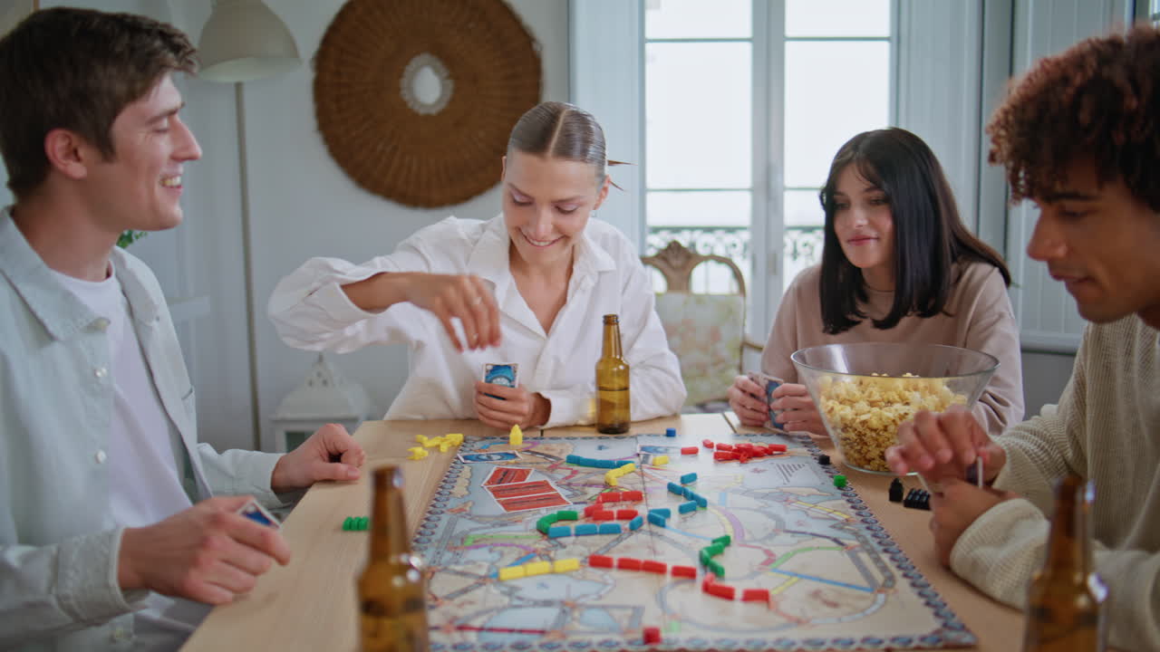 Youngsters play board game on kitchen closeup. Diverse friends sitting at table