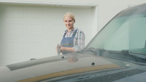 a woman washing my car in the backyard of her house on the background of the doors to the garage