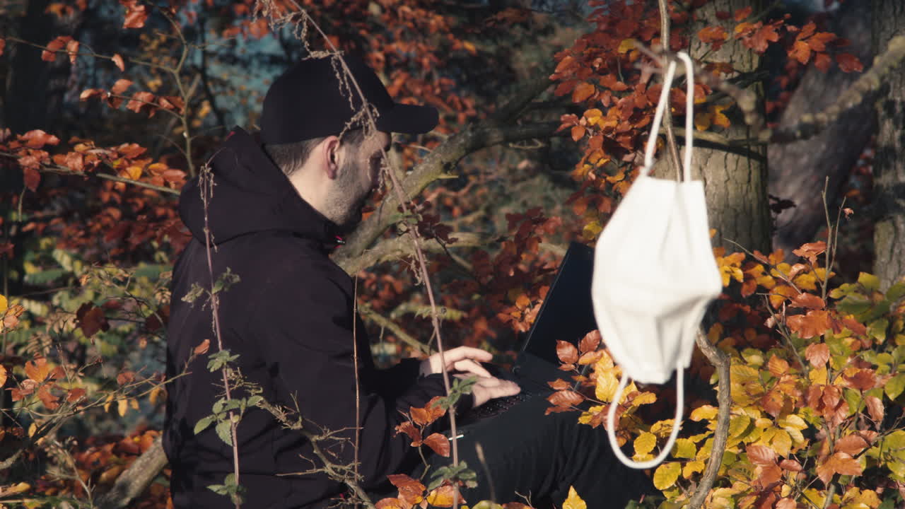 covid 전염병, 일중독 개념 동안 외부에서 노트북을 사용하는 남자