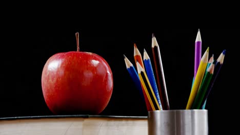 apple on book with color pencil on table