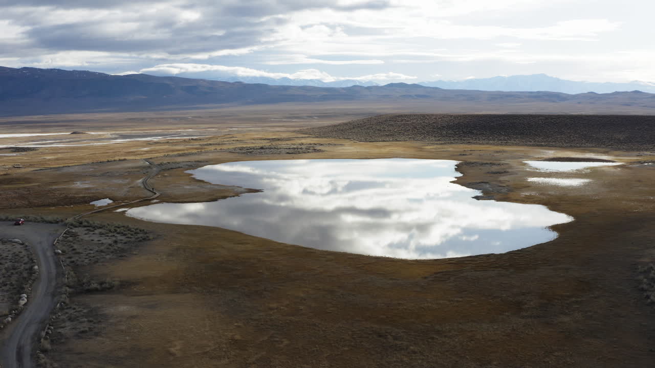 маленькое озеро посреди пустынного ландшафта, отражающее облака в небе