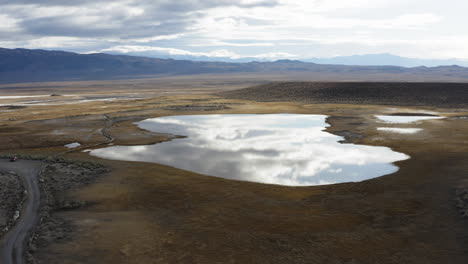 Kleiner-See-Inmitten-Einer-Wüstenlandschaft,-In-Der-Sich-Die-Wolken-Am-Himmel-Spiegeln