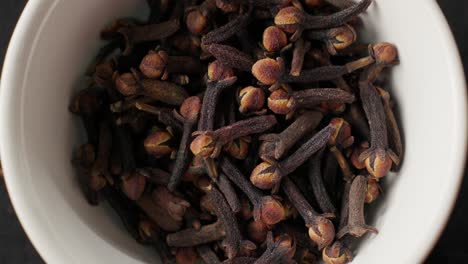 dried cloves falling into a white bowl