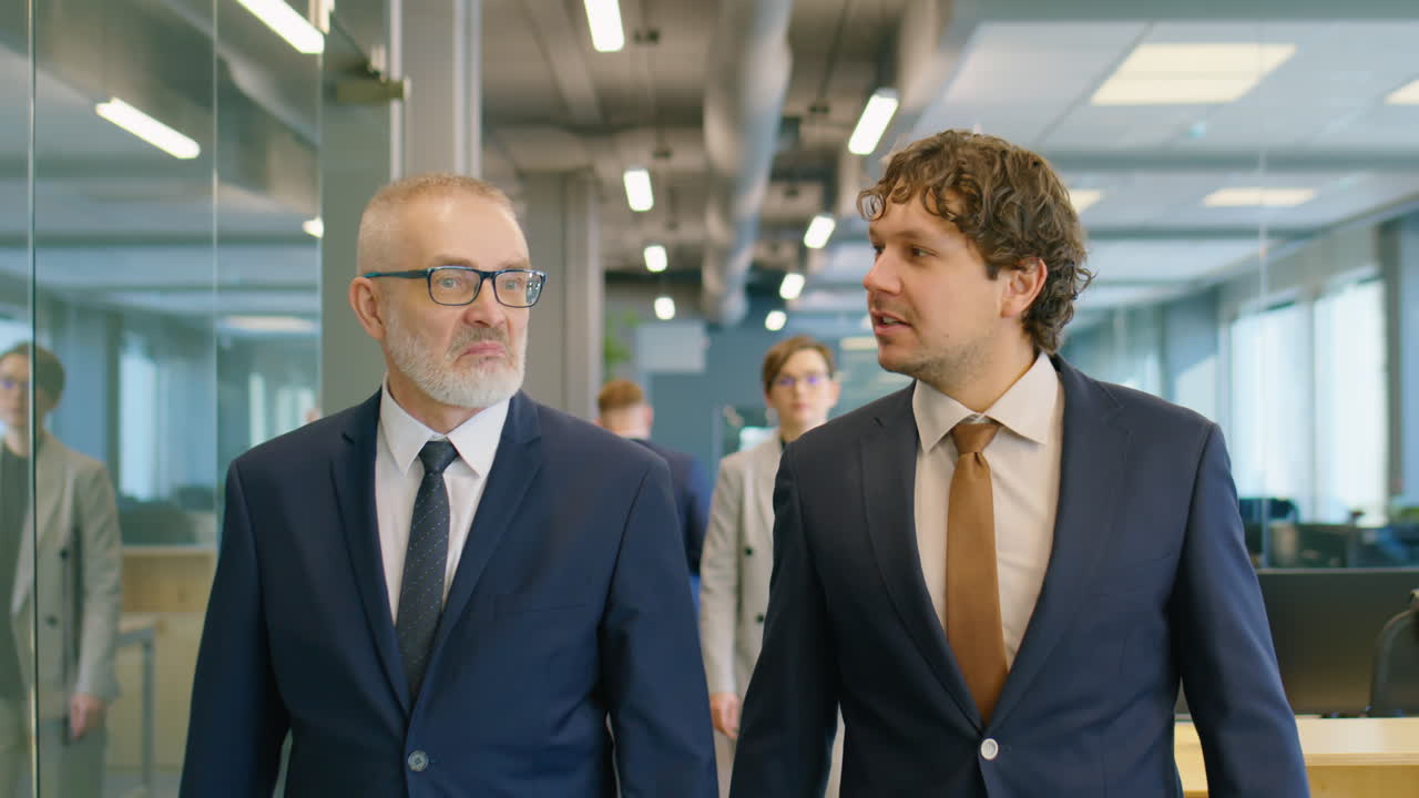Dos empresarios caminando por la oficina y hablando.