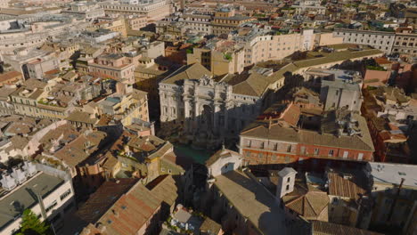 Forwards-fly-above-beautiful-historic-city-centre.-Revealing-famous-baroque-Trevi-Fountain-with-sculptures-and-tilt-up-for-cityscape.-Rome,-Italy