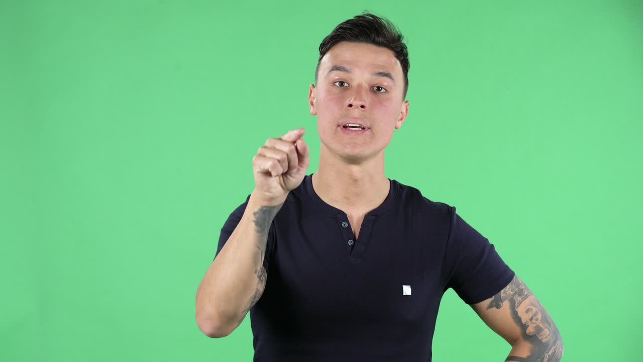 Portrait of a handsome young guy looking straight is says that he is not guilty and blames someone. Green screen