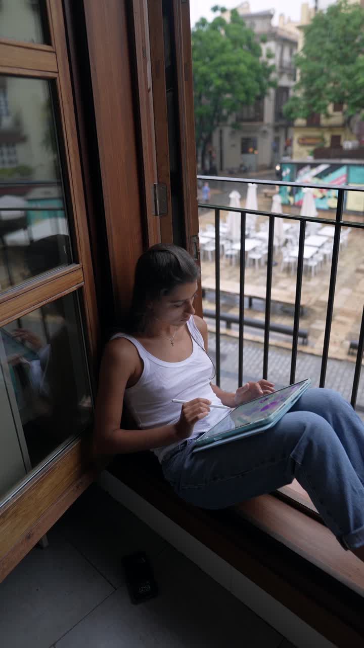 mujer trabajando en una tableta en el balcón con vista a la ciudad