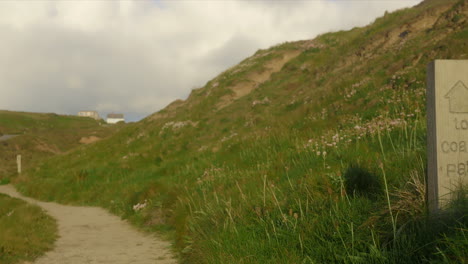 view of coastal path sign heading to the walkway ready to explore at golden hour, panning shot