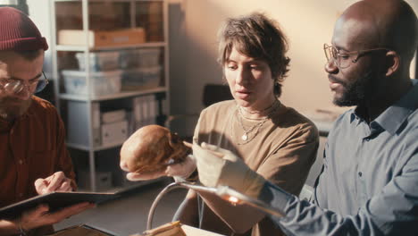 team of archaeologist examining skull and drawing sketch in laboratory