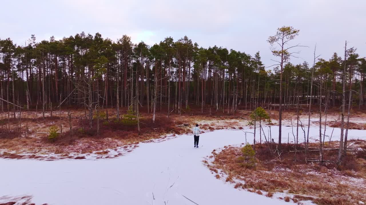 Drone follows man skating across winding frozen bog tracks in sunrise in Latvia