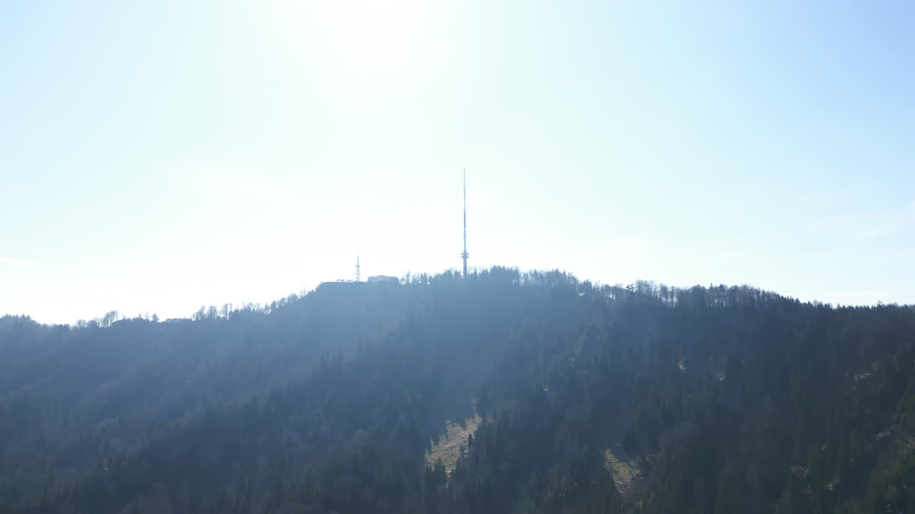 Aerial: Uetliberg TV Tower with sun shining during the day in Zurich, Switzerland, establishing drone shot
