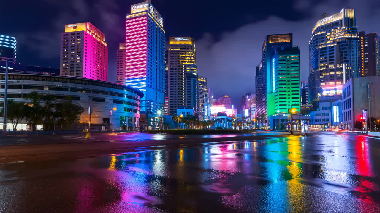 Horizonte Urbano Iluminado Por Neon Refletindo No Pavimento. Ruas Encharcadas Pela Chuva Espelham Fachadas Coloridas De LED De Imponentes Edifícios