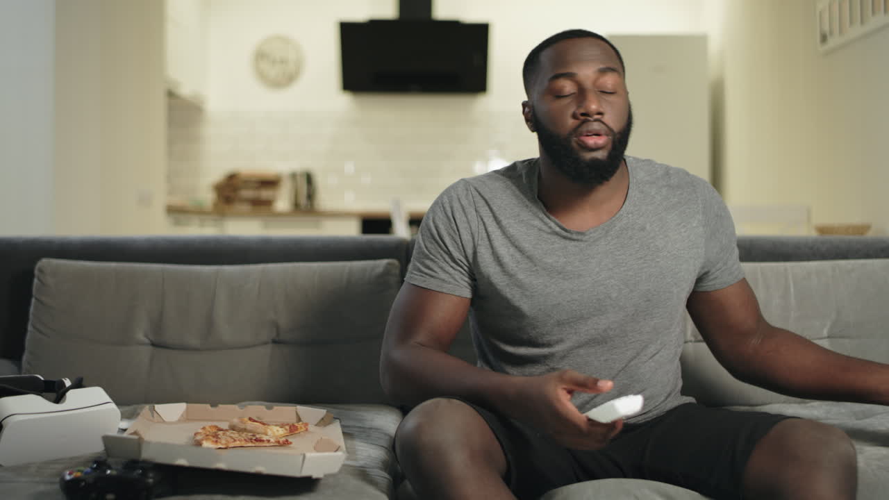 African man searching tv program in kitchen. Smiling man reading message at phone