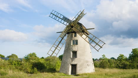 Aerial-shot-of-an-old-windmill-made-of-stone-and-wood-on-Gotland,-Sweden