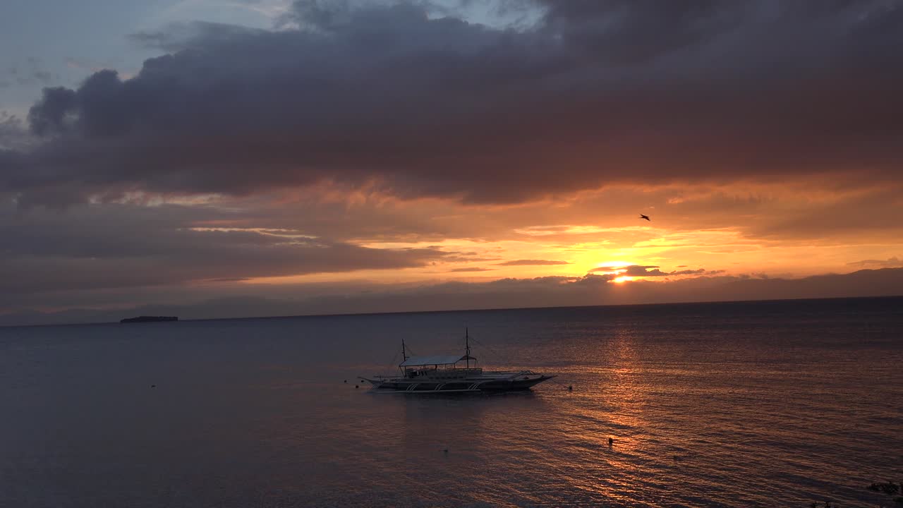백그라운드에서 작은 섬과 전경에서 전통적인 필리핀 보트와 필리핀에서 바다 일몰