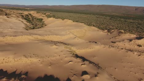 vista aérea de dunas de arena masivas entre montañas rocosas en la región árida del cabo norte, sudáfrica