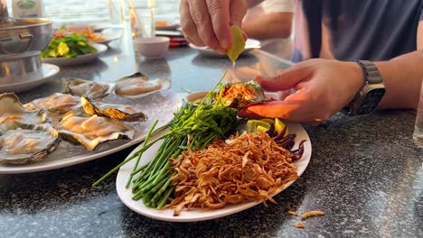 hands preparing seafood with lime and herbs