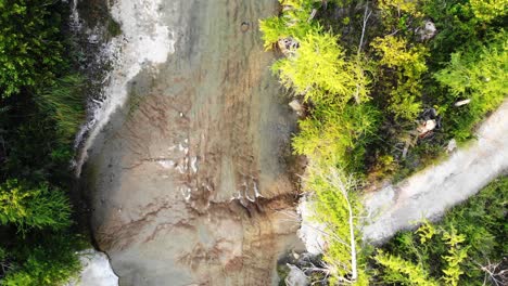 Aerial---rising-high-above-top-down-view-of-the-river-where-water-is-breaking-into-3-strands-forming-small-waterfalls