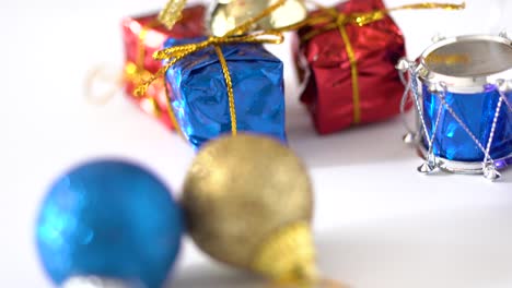 Close-up-view-and-panning-studio-shot-of-Christmas-decorations-on-white-background-:-Golden-ribbons,-bell,-Snare-Drum-and-shining-ball