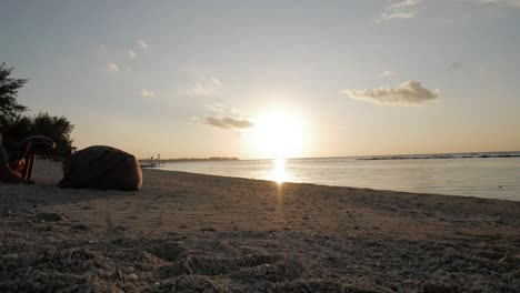 time lapse of indonesian sunset,view from gili air island with many tourists crossing sandy beach.