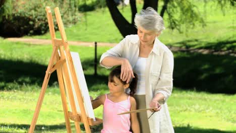 Young-child-painting-a-canvas-with-grandmother