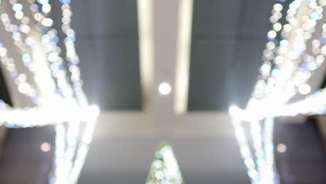 many luminous led bulbs are indoors. these are used in christmas decorations. tilt shot from top to bottom. out of focus. look up. in the center of the screen is a green christmas tree.