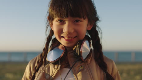 close up portrait of little asian girl on seaside park smiling cheerful making faces at camera enjoying fun