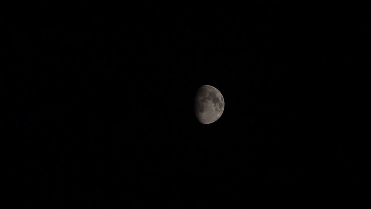Vista em timelapse da fase gibosa crescente da Lua passando contra o céu noturno escuro