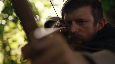 man aiming with a bow and arrow in a forest