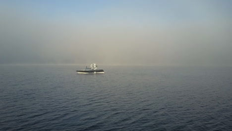 Low-aerial-flight-to-water-ski-motorboat-on-quiet-foggy-lake-in-Canada