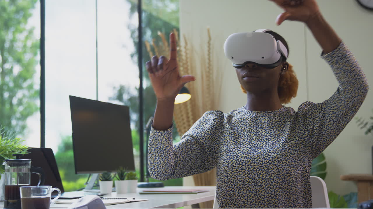 Woman Working From Home Office At Desk Wearing VR Headset Interacting With AR Technology