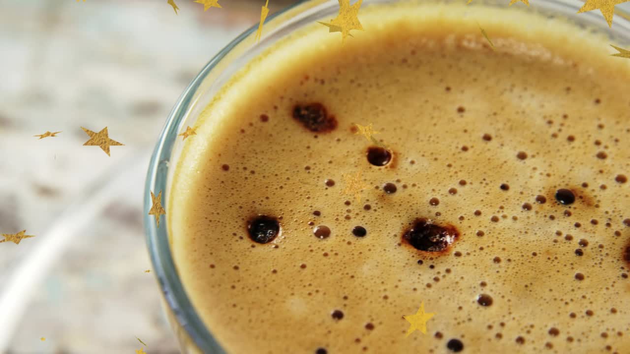 커피 거품 크레마의 기포가 클로즈업으로 드러나면서 표면 위로 떠다니는 황금색 별 모양이 보여요