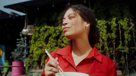mujer comiendo fideos al aire libre